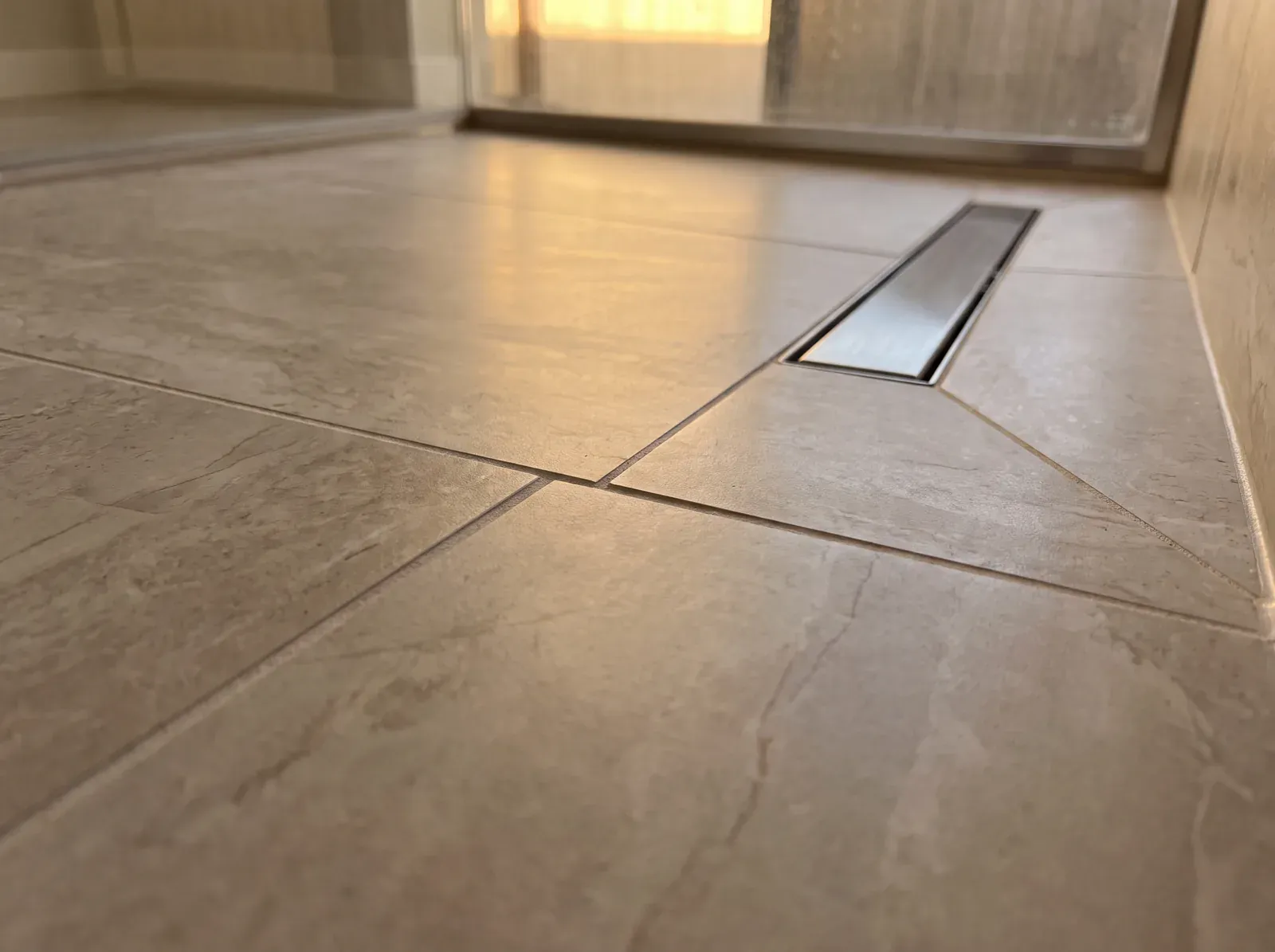 Completed curbless shower threshold with linear drain, tile flowing from bathroom floor into the shower at grade