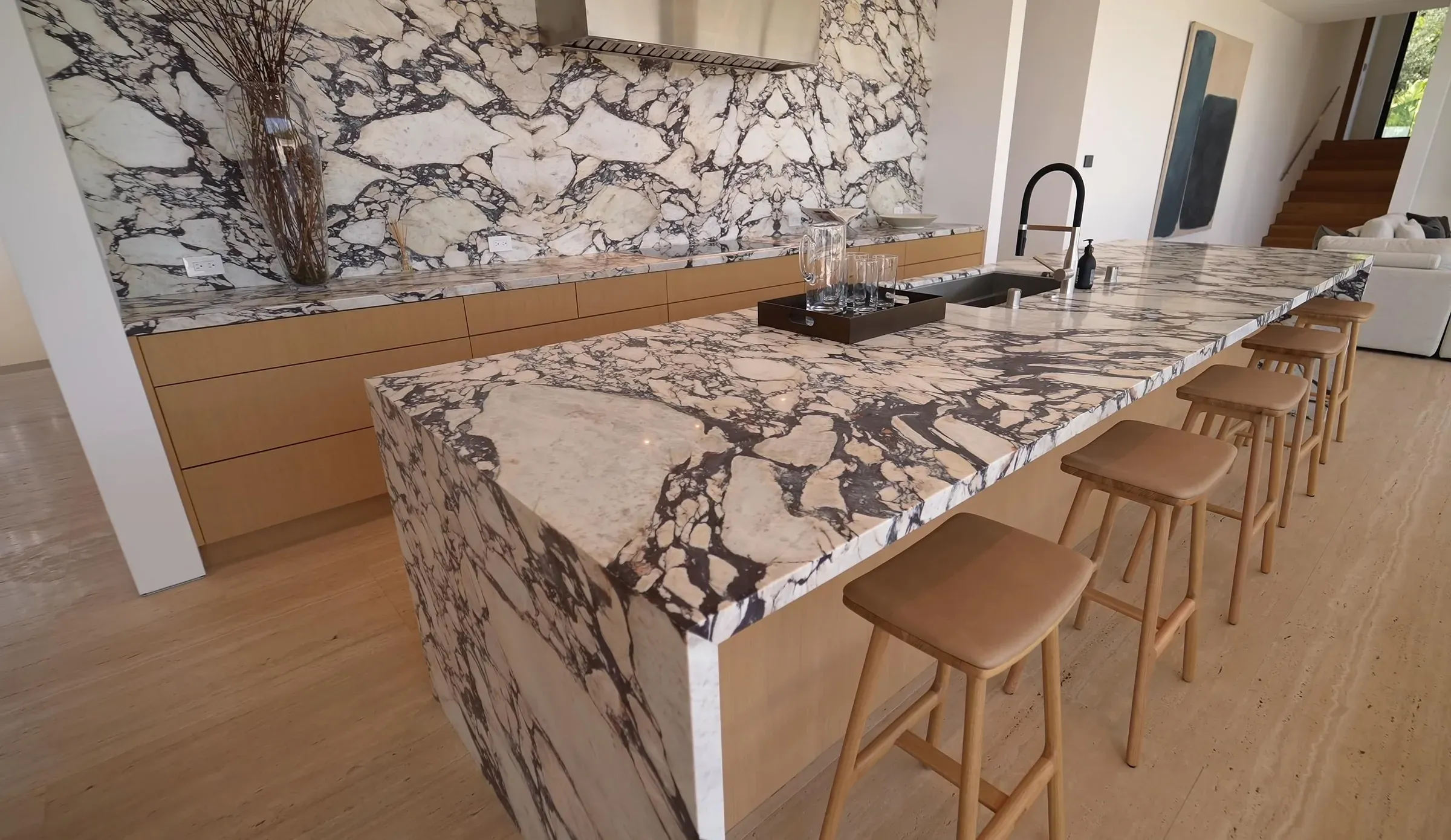 Kitchen with a marble waterfall island, pale cabinetry, and natural light