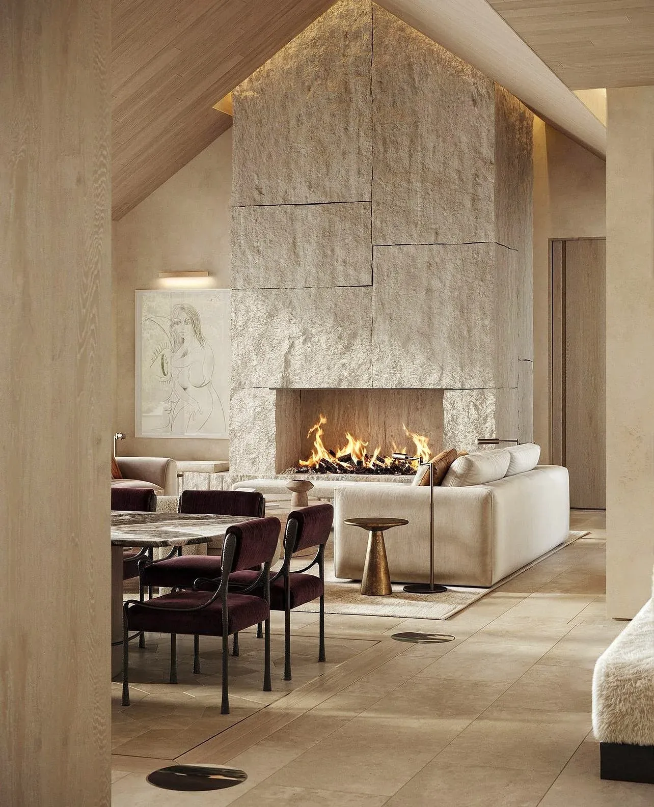 Vaulted living and dining room with a full-height stone fireplace and limestone floors