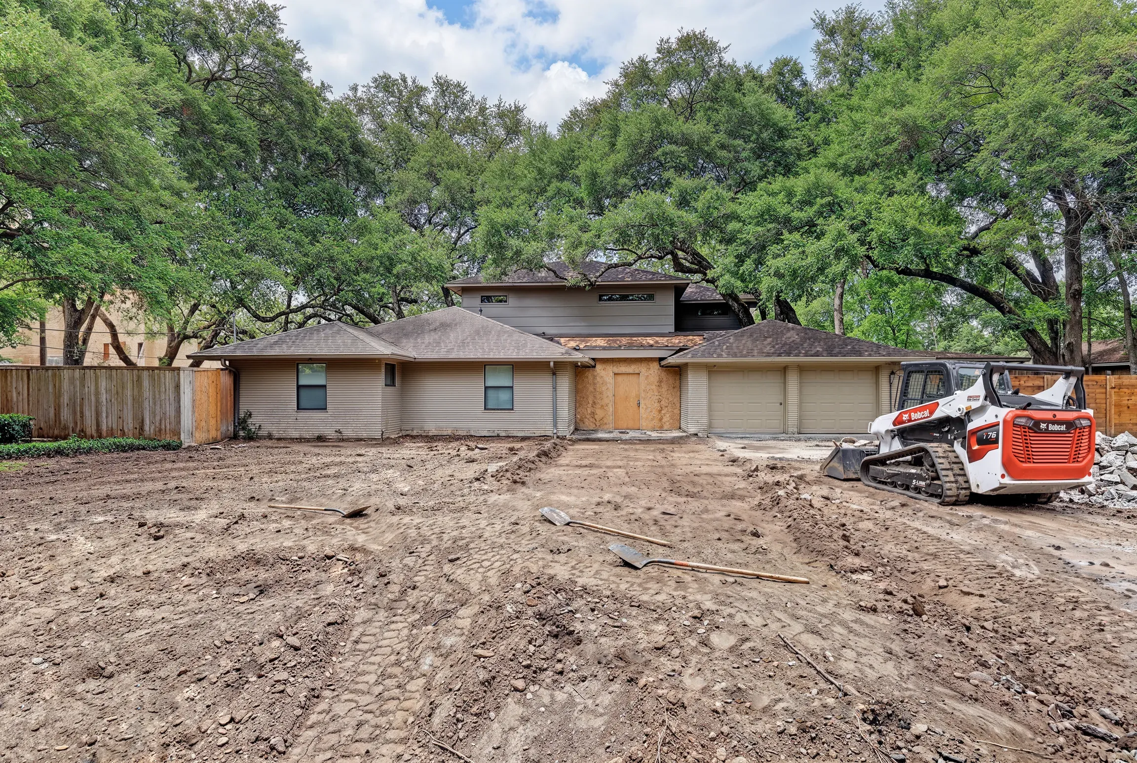 The front yard before: bare graded dirt across the whole lot with a skid steer parked at the driveway