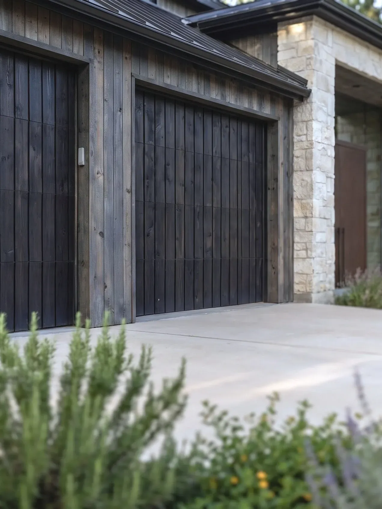 Garage conversion in Austin, TX with charred wood door bays and limestone masonry