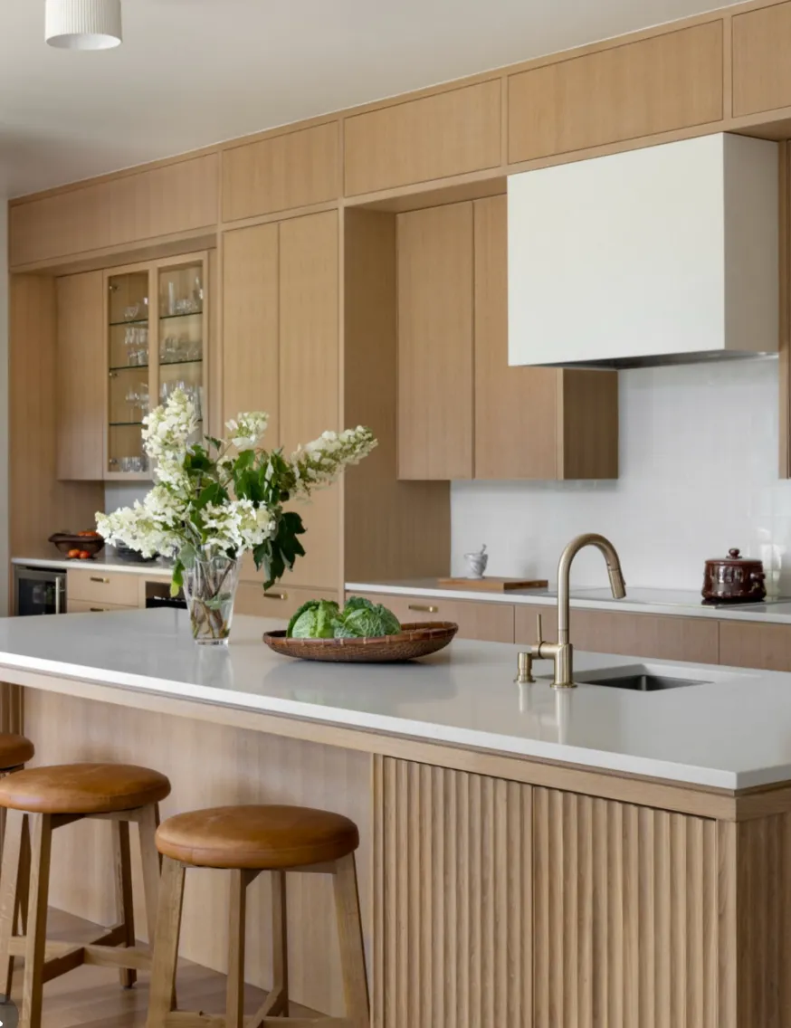 Remodeled kitchen with pale oak cabinetry, glass-front uppers and a long island