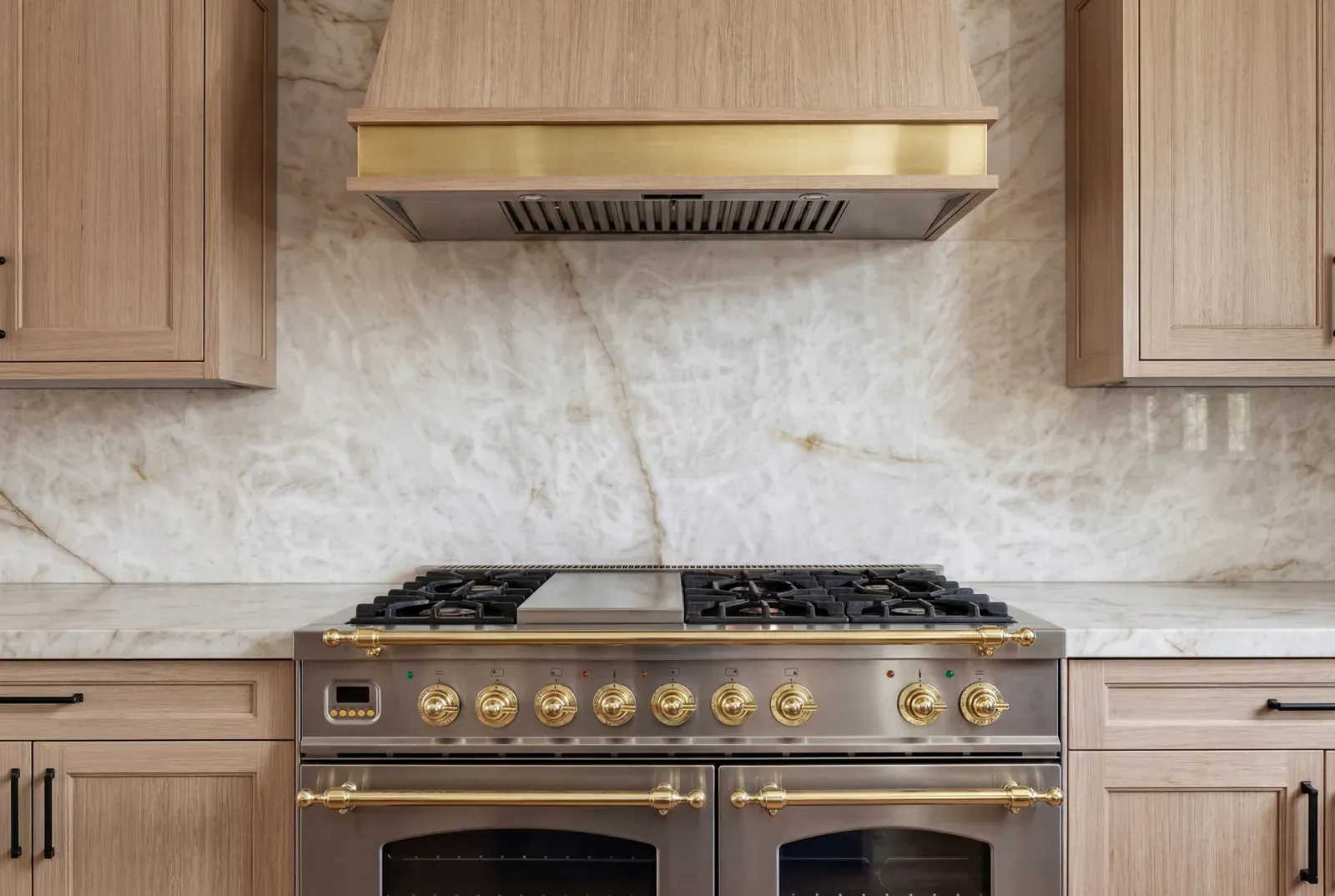 Professional gas range under a white oak hood with a full quartzite slab backsplash in a Hyde Park kitchen remodel