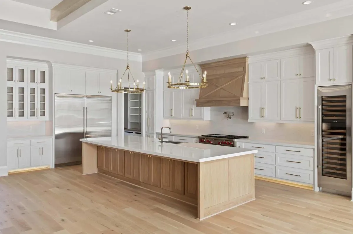 Finished kitchen with a white oak island, wood range hood, and twin ring chandeliers