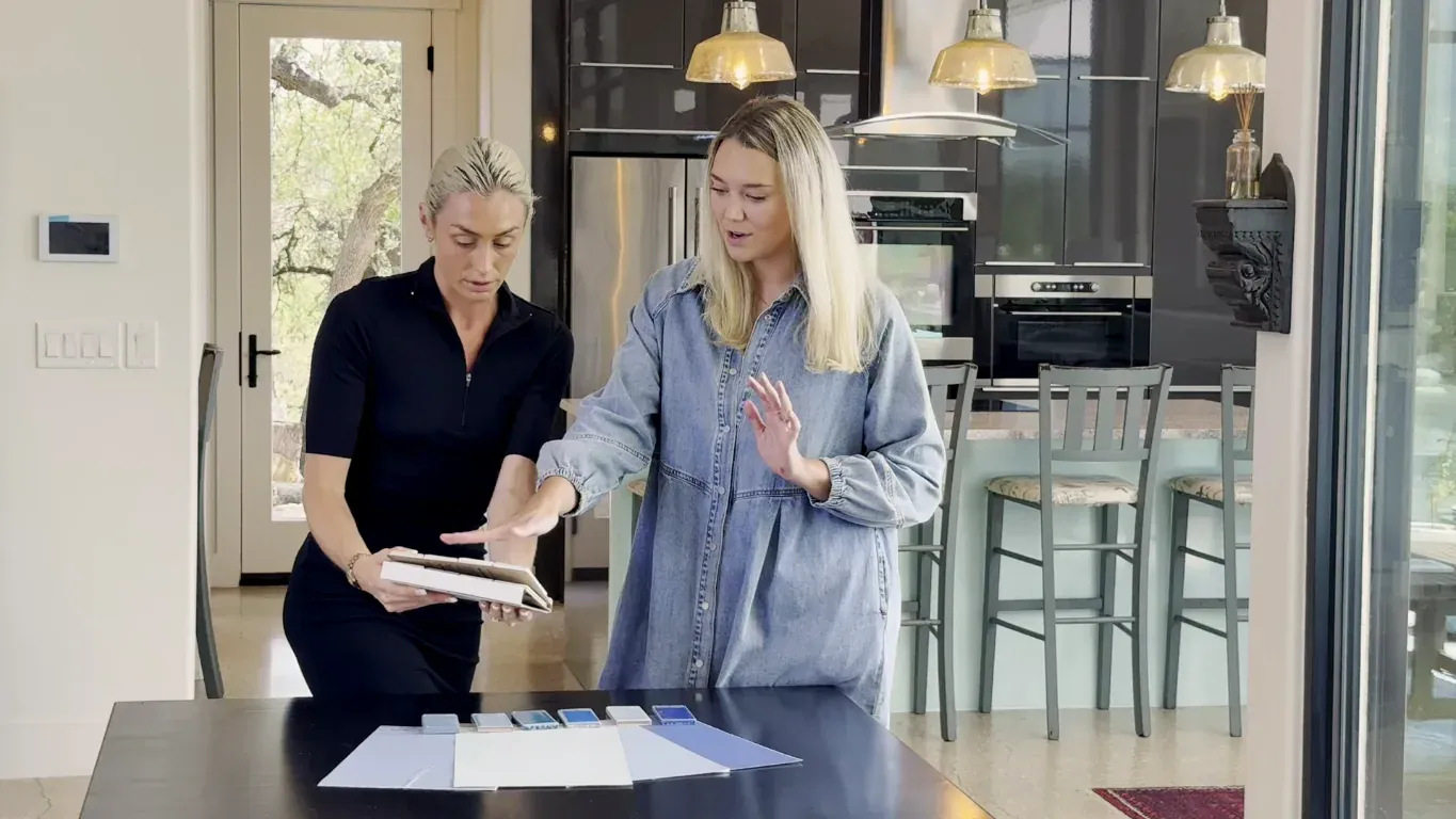 Two people reviewing drawings and material samples at a kitchen counter during a design meeting