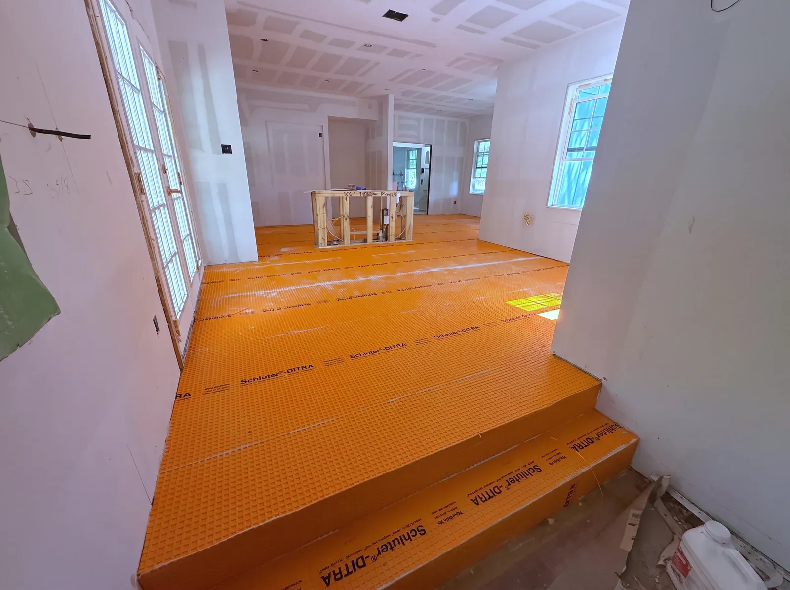 Orange waterproofing membrane covering the floor and steps of a room framed and drywalled during construction